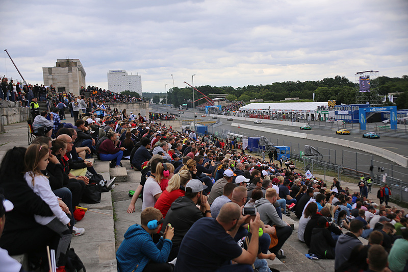 順位争いで連なるマシンを観戦する観客