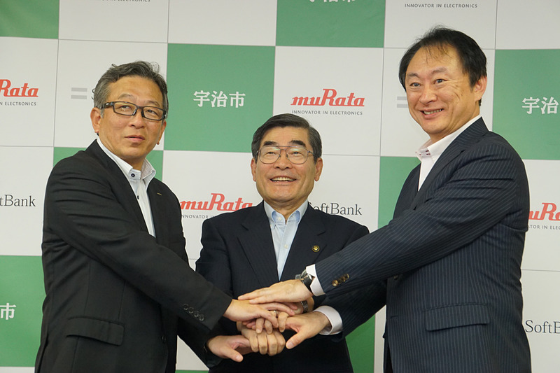 「Iotを活用して路面情報を検知する実証実験に関する説明会」に出席した、株式会社村田製作所 取締役常務執行役員 岩坪浩氏（左）、宇治市 市長の山本正氏（中央）、ソフトバンク株式会社 執行役員 広域法人第二営業本部 本部長 清水繁宏氏（右）