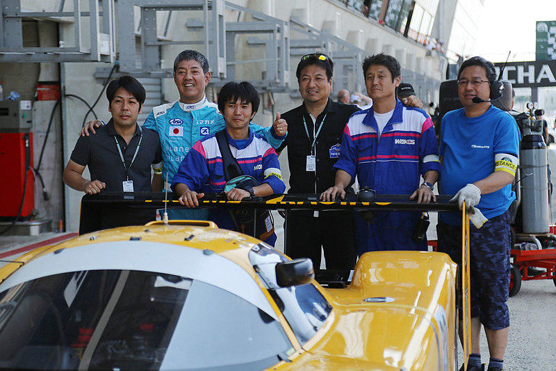 複雑な表情で記念撮影する日産 R90 CK（1990年）と久保田克昭氏、クルー