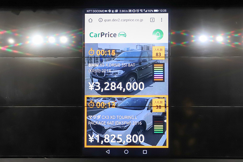 売り主がスマートフォンで閲覧できるオークション画面。オレンジの枠はオークション終了が近いことを、緑色の画面は入札があったことをそれぞれ示している。画面右側のゲージは、ウリキリ価格を超えると虹色に光る