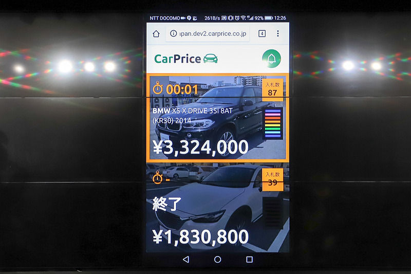 売り主がスマートフォンで閲覧できるオークション画面。オレンジの枠はオークション終了が近いことを、緑色の画面は入札があったことをそれぞれ示している。画面右側のゲージは、ウリキリ価格を超えると虹色に光る