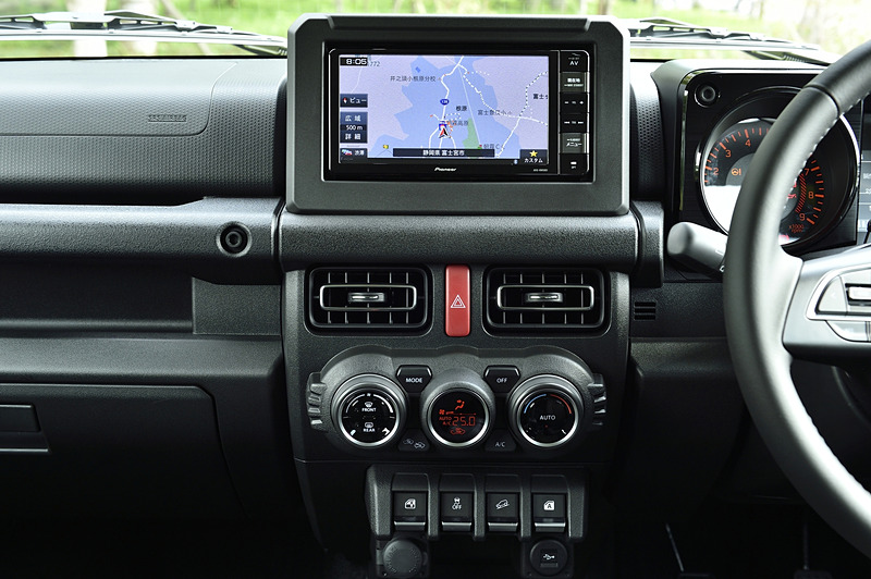 水平基調としたジムニーのインテリア。グローブをしたままでも操作しやすいような大型の集合スイッチやエアコンダイアルを採用。運転席と助手席の間には副変速機をレイアウト