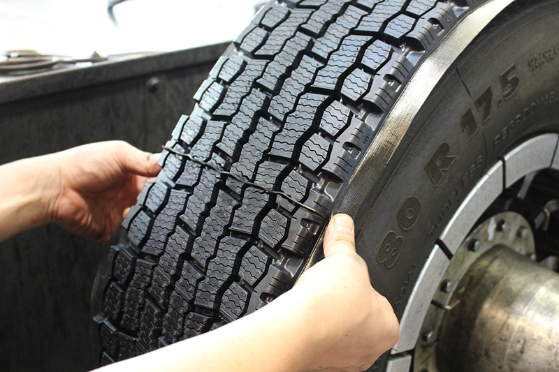 タイヤを回転させながらトレッドゴムを貼り付け、カットされたトレッドパターンの断面が両端で合うよう見極めながら作業が進められている