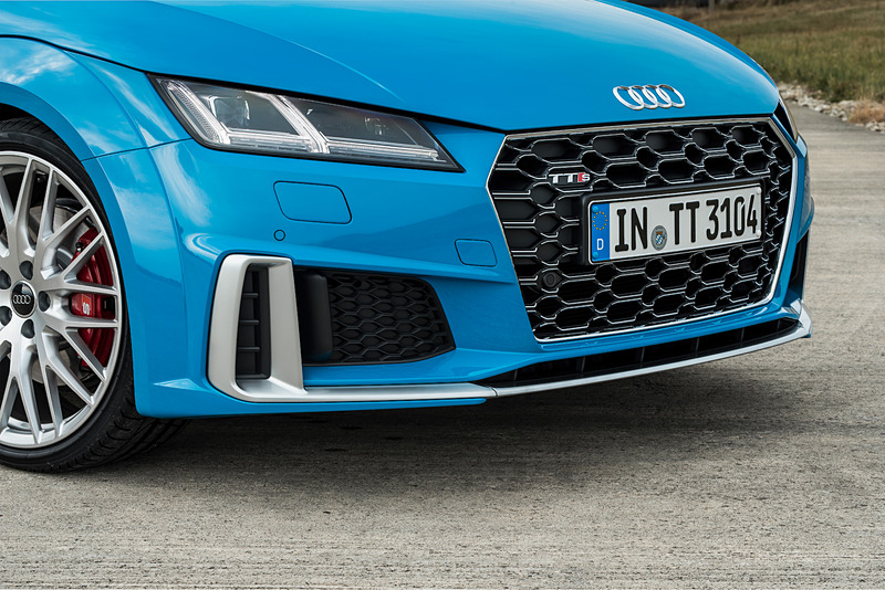 TTS クーペのエクステリアでは、シングルフレームグリルがマットシルバー＆マットブラックで構成されるとともに、アルミニウム調で仕上げられたワイドなフロントスプリッター、バーティカルエアインレット、トリムストリップなどを採用。リアまわりでは立体的なディフューザー、4本出しのテールパイプがデザインハイライトになる