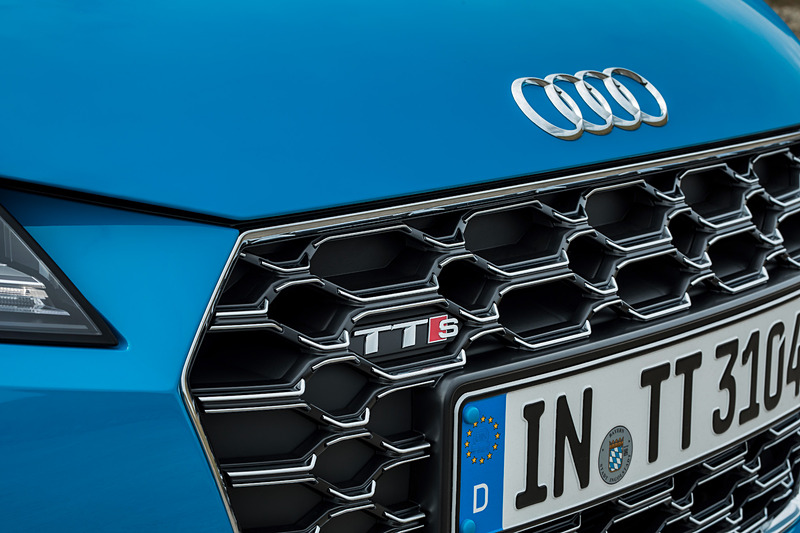 TTS クーペのエクステリアでは、シングルフレームグリルがマットシルバー＆マットブラックで構成されるとともに、アルミニウム調で仕上げられたワイドなフロントスプリッター、バーティカルエアインレット、トリムストリップなどを採用。リアまわりでは立体的なディフューザー、4本出しのテールパイプがデザインハイライトになる