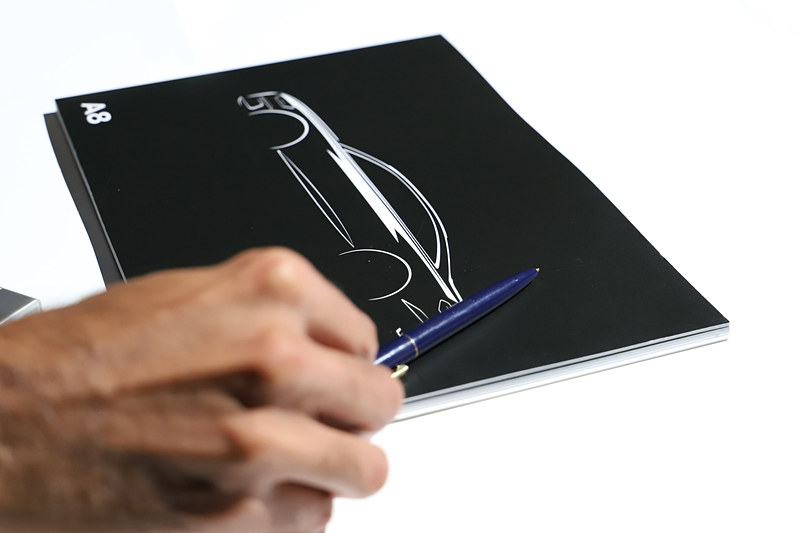 インタビュー中には実車が近くになかったので、ファヤ氏はカタログの表紙を使ってリアバンパーの角度について説明した。このカタログのスケッチはファヤ氏が描いたものだという