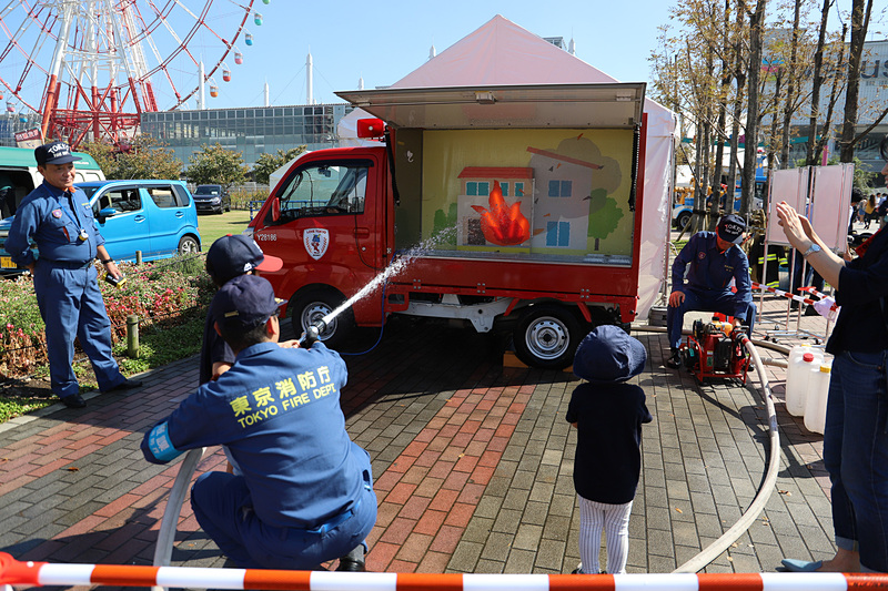 東京消防庁は「まちかど防災訓練車」と呼ばれる小型の車両を使った消火体験を実施。子供用の制服を着ての記念撮影だけでなく、消火体験をすることも可能