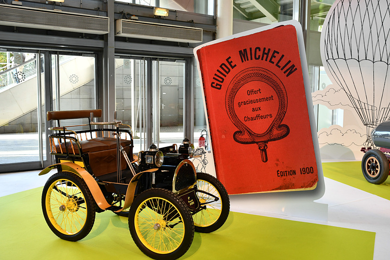 1898年製 ルノー 1号車の後ろには、1900年版のミシュランガイドをデザインした背景を用意。時代の雰囲気を感じやすいようにしていた
