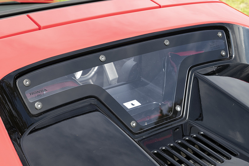 リアには透明のポリカーボネート製のウィンドウを配置。エンジンフードを開ける場合は室内側から矢印部分に手を入れてラッチを外す必要がある