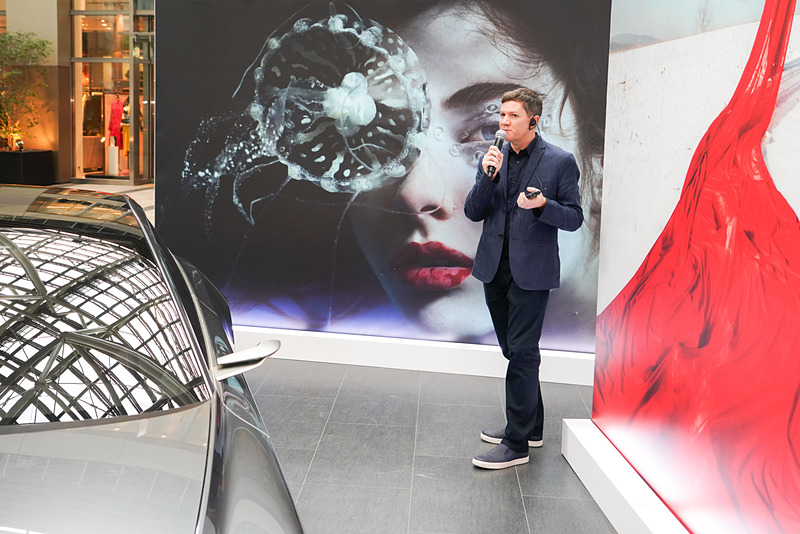 フォトアートの前で解説を行なうマイケル・ヴァン・ホーン氏。奥がパリを拠点に女性ポートレートを多く撮影するMarta Bevacqua氏の作品。右手前はロンドンで活動するAndrew Tarnwczyk氏の赤い布をまとったミステリアスなセルフポートレート