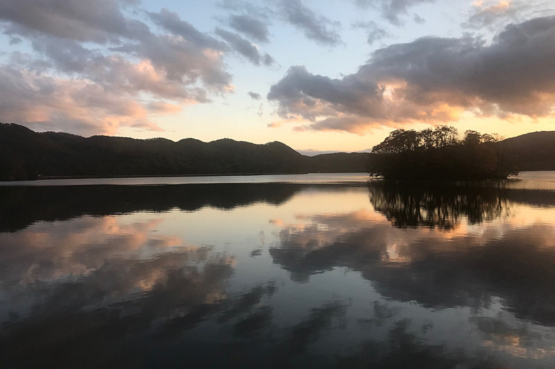 夕焼けを鏡のように映す大沼