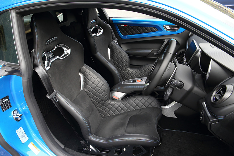 マットカーボン/アルミ/レザーを組み合わせるピュアグレードのインテリア。1脚あたり13.1kgという軽量を誇るSabelt製モノコックバケットシートをはじめ、レザーステアリング/ブルーステアリングセンタートリム、FOCAL製軽量4スピーカーなどを標準装備