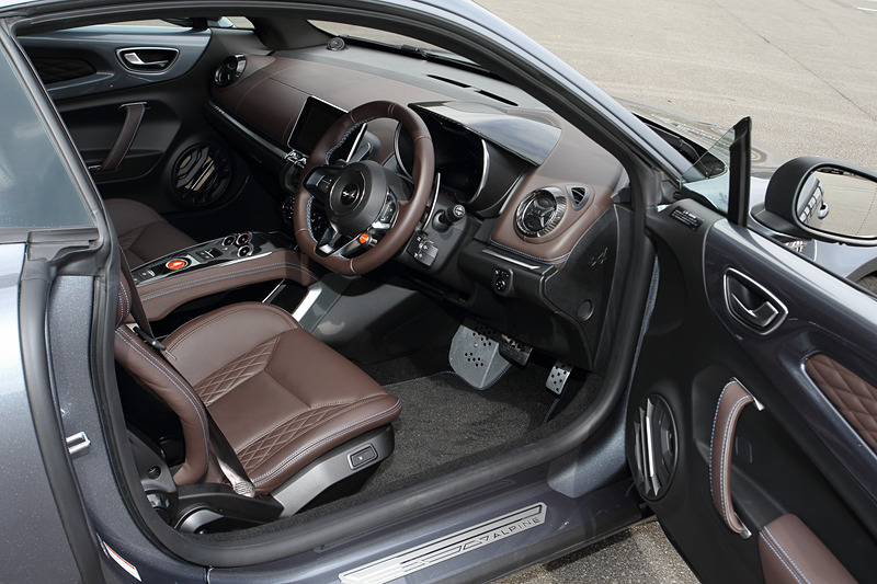 ブリリアントカーボン/アルミ/レザーを組み合わせるリネージグレードのインテリア。ブラウンレザーのSabelt製スポーツシート（シートリフター・リクライニング、シートヒーター付き）のほか、レザーステアリング/ブラックステアリングセンタートリム、FOCAL製軽量4スピーカー＋サブウーファーなどが専用装備になる