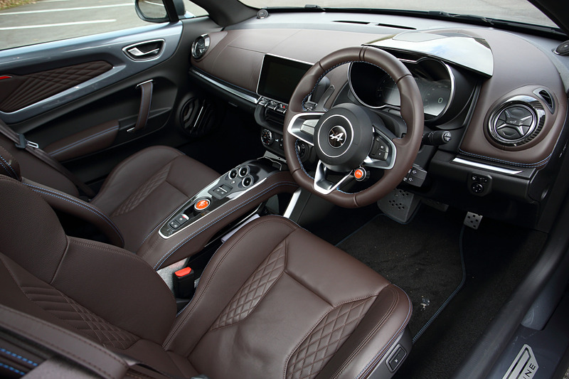 ブリリアントカーボン/アルミ/レザーを組み合わせるリネージグレードのインテリア。ブラウンレザーのSabelt製スポーツシート（シートリフター・リクライニング、シートヒーター付き）のほか、レザーステアリング/ブラックステアリングセンタートリム、FOCAL製軽量4スピーカー＋サブウーファーなどが専用装備になる