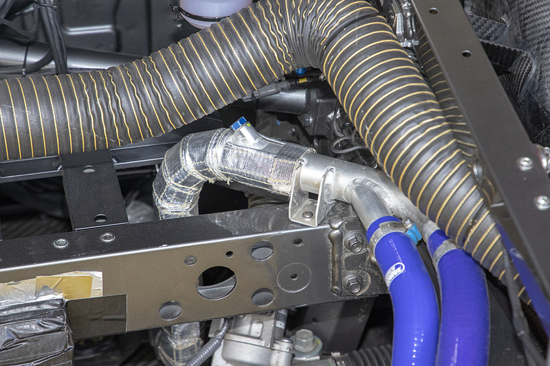 NSX GT3はラジエターが車両前方にあり、そこからリアのエンジンへ冷却水パイプが伸びている。ラジエターを出た後のところでパイプに遮熱布が巻いてあったのが気になり、チーフメカニックの新保氏に理由を聞いてみると、フロア下を通る冷却水パイプからの熱でフロアが熱くなるので、ドライバーから対策の要請が出たためとのことだった