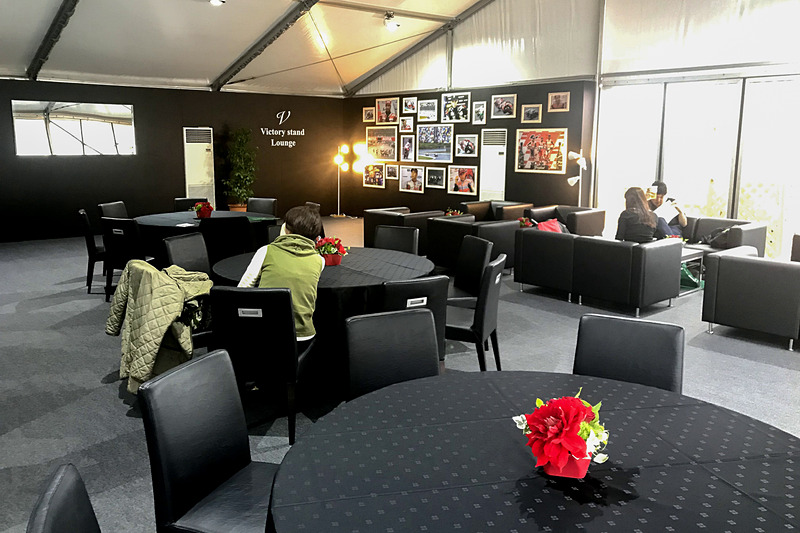 広々としたビクトリースタンドラウンジは空調完備。壁のモニターにはコース上の映像のほか、ラップタイムなども表示されるので、居ながらにしてレースの状況を知ることができる