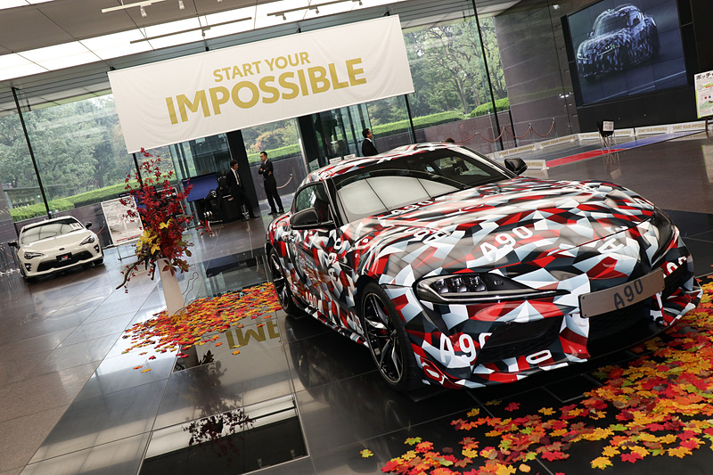 トヨタ自動車の東京本社1階にあるロビースペースの中央で、新型スープラの試作車を車両展示。紅葉（模造品）をイメージした季節感のある展示となっていた