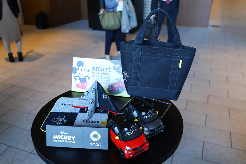 限定コレクションの「ミニトートバッグ」（右上）と、「ハンカチタオル」（左下）。ハンカチタオルはレッドとイエローの2色展開