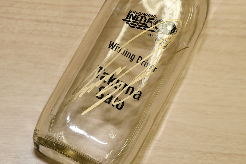 牛乳瓶には佐藤琢磨選手所有の金色のペンでサイン。牛乳瓶には金ペンが映えるとのこと