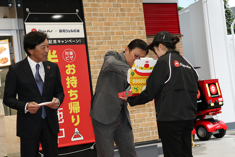 テープカットに続いて行なわれたのは、ピザハットの新店舗がオープンする時の恒例行事となっている「ファーストバイト」。同じく12月14日にオープンするピザハット代々木の店内で焼き上げられたばかりのピザを4人そろって味わった