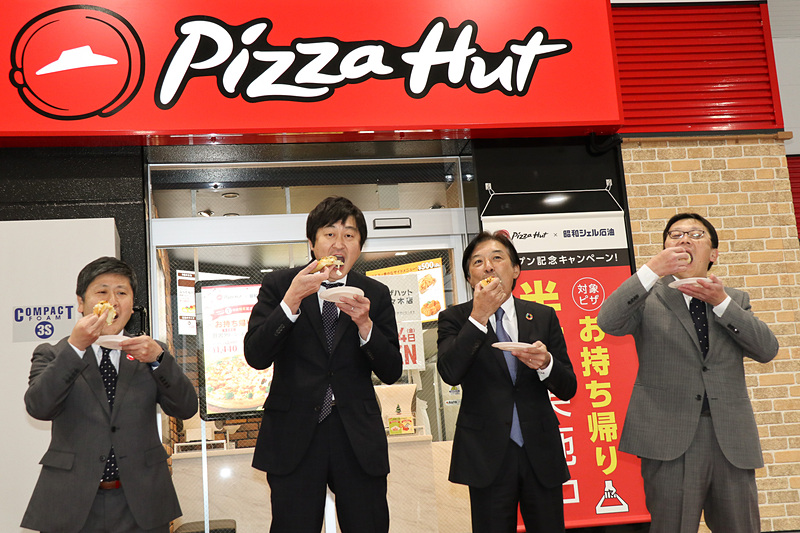 テープカットに続いて行なわれたのは、ピザハットの新店舗がオープンする時の恒例行事となっている「ファーストバイト」。同じく12月14日にオープンするピザハット代々木の店内で焼き上げられたばかりのピザを4人そろって味わった