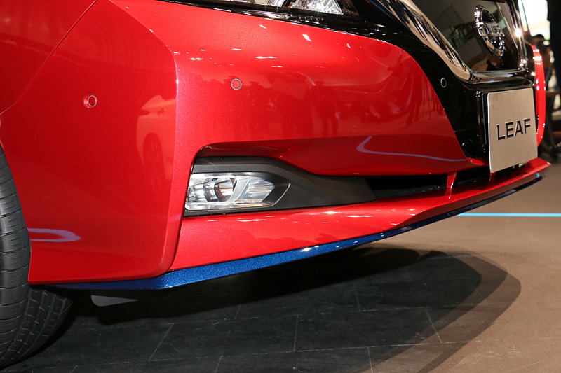 リーフ e＋では車高が5mm高まり、走行用バッテリーの張り出しで最低地上高が15mm低下していることからフロントバンパー下側の形状を変更。ブルー塗装のリップスポイラーも追加された