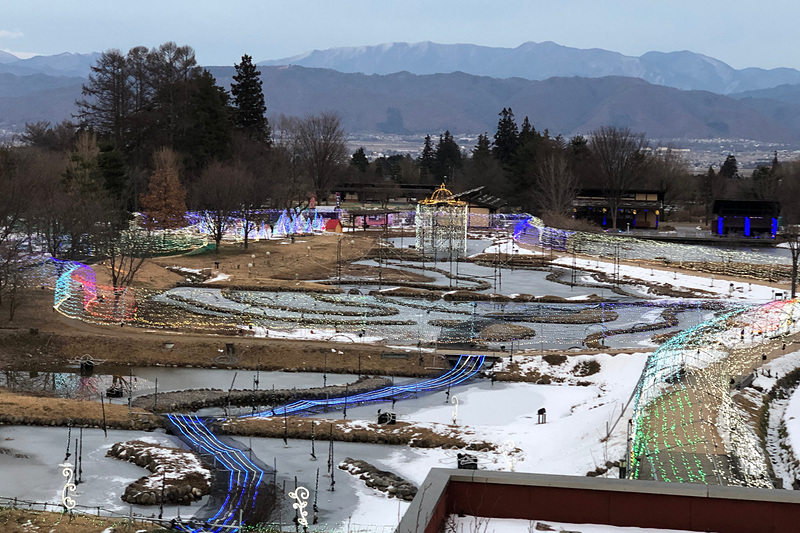 長野県安曇野市にある「国営アルプスあづみの公園」堀兼・穂高地区のイルミネーション。これは16時45分ごろの写真で、まだちょっと明るくてイルミネーションが目立ちませんが、背景の山々との壮大な光景が印象的でした。日本最長500mの光のトンネル、歩いてみたかったなぁ～
