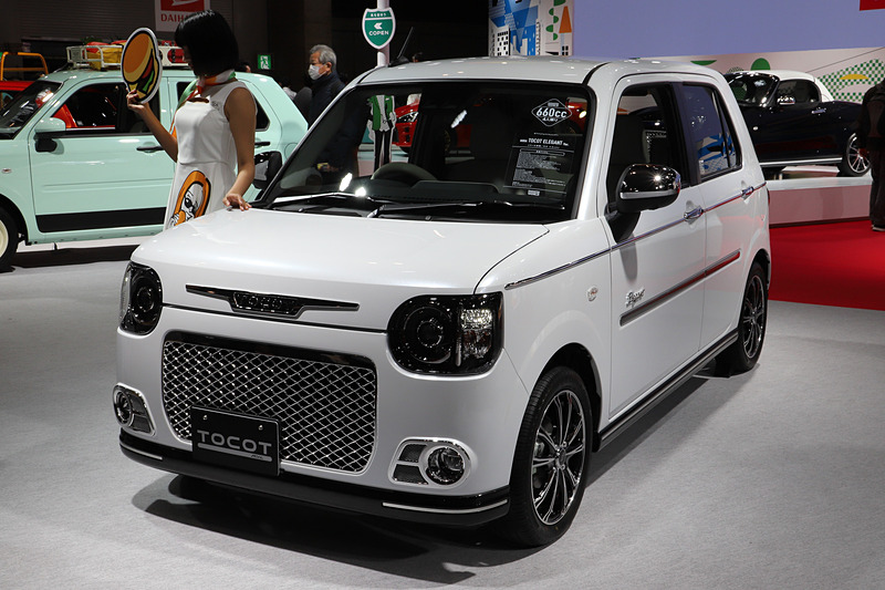 ホワイトのボディカラーに映えるフロントフードオーナメントやドアミラーカバー「メッキ」、サイドモール「メッキ」、専用エンブレム（サイド）などを装着した「ミラ トコット エレガント Ver.」