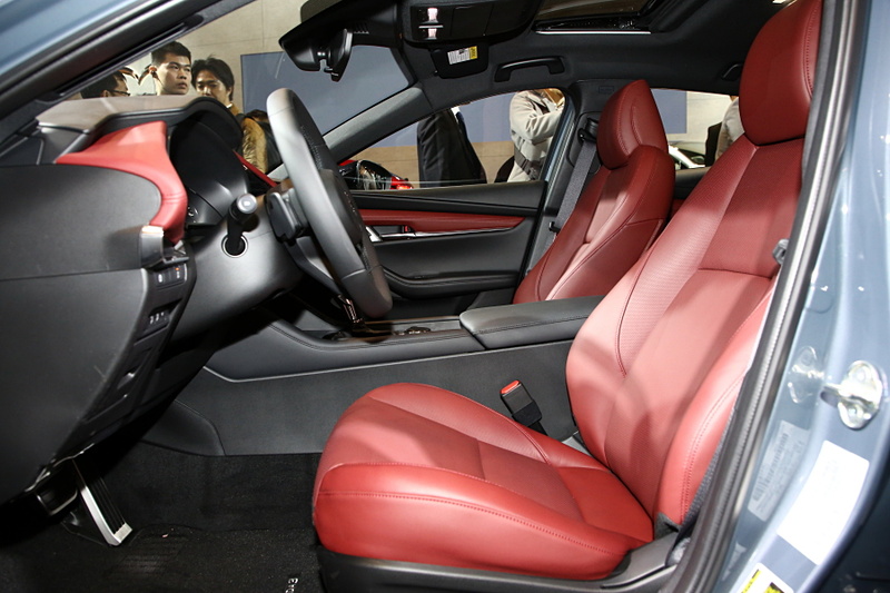 ハッチバック専用色となる「ポリメタルグレーメタリック」に塗装された新型Mazda3 CUSTOM STYLE（北米仕様ベース）。インテリアカラーはバーガンディで、マツダの新たな世界観を表現。エクステリアでも専用のエアロパーツを装備していて、ステージに飾られた「ソウルレッドクリスタルメタリック」や「マシーングレープレミアムメタリック」の新型Mazda3とは異なったテイストを醸している