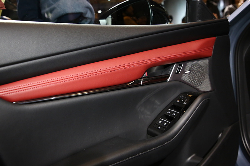 ハッチバック専用色となる「ポリメタルグレーメタリック」に塗装された新型Mazda3 CUSTOM STYLE（北米仕様ベース）。インテリアカラーはバーガンディで、マツダの新たな世界観を表現。エクステリアでも専用のエアロパーツを装備していて、ステージに飾られた「ソウルレッドクリスタルメタリック」や「マシーングレープレミアムメタリック」の新型Mazda3とは異なったテイストを醸している
