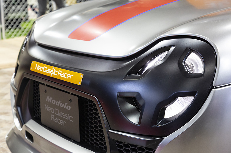 ヘッドライトテーピングをモチーフにしたグリル一体型ライトカバー。センターには革ベルトにNeo Classic Racerの車名を印刷して配置