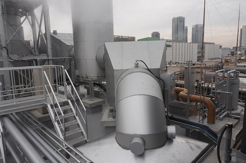 ガスエンジンは建物内にあるが、排出ガスは屋上に向け、騒音の低減などを図っている。48万3000ccのエンジンだけに消音装置も大きい。ふそうのディーゼルエンジンと同様に尿素による排出ガス浄化システムも備わっている。取材時は気温が低かったため湯気となっているが、特に匂いなどはなかった