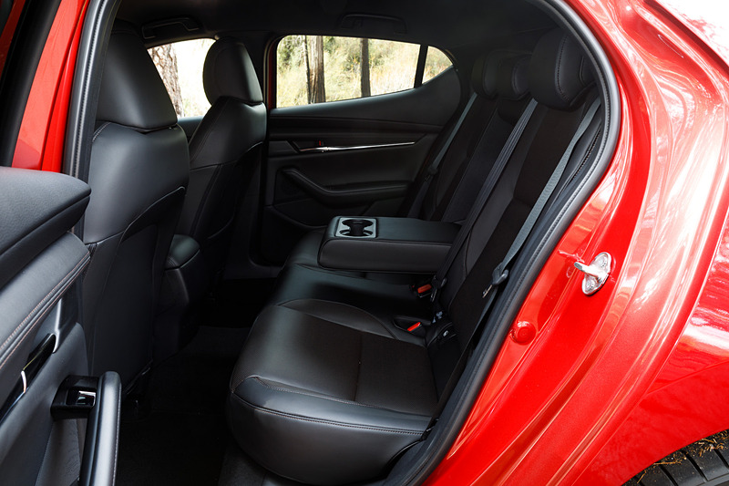 5ドアハッチバックのインテリア。新型Mazda3のコクピットはすべてをドライバーを中心に左右対称にレイアウト。ステアリングスポークやセンターディスプレイなど、パーツ単位で「バニシングポイント」（遠近法で言う収束点）に基づいてデザイン。また、本革にはマツダ独自のシボを採用したほか、シフトパネルにはレーザー加工で柄を刻み込んだ黒のメタリック層と、まっすぐ光を透過・減衰させるカラークリア層からなる2層成形と呼ばれる技術を採用