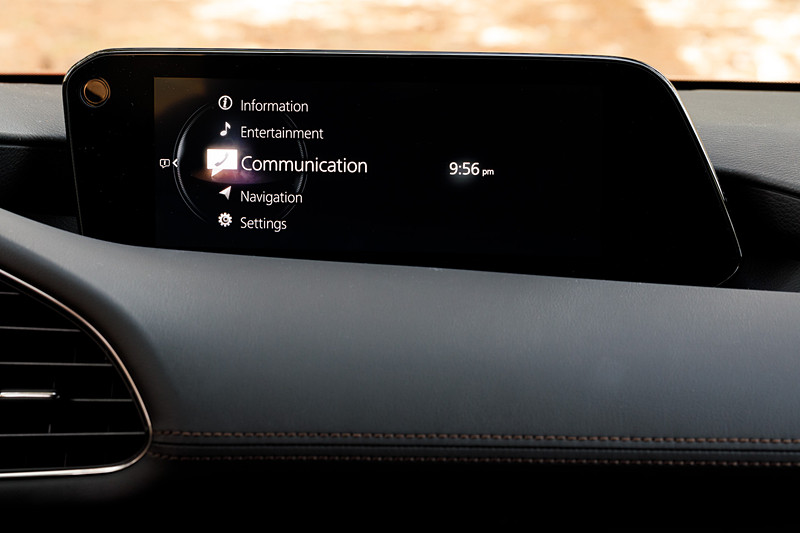 5ドアハッチバックのインテリア。新型Mazda3のコクピットはすべてをドライバーを中心に左右対称にレイアウト。ステアリングスポークやセンターディスプレイなど、パーツ単位で「バニシングポイント」（遠近法で言う収束点）に基づいてデザイン。また、本革にはマツダ独自のシボを採用したほか、シフトパネルにはレーザー加工で柄を刻み込んだ黒のメタリック層と、まっすぐ光を透過・減衰させるカラークリア層からなる2層成形と呼ばれる技術を採用