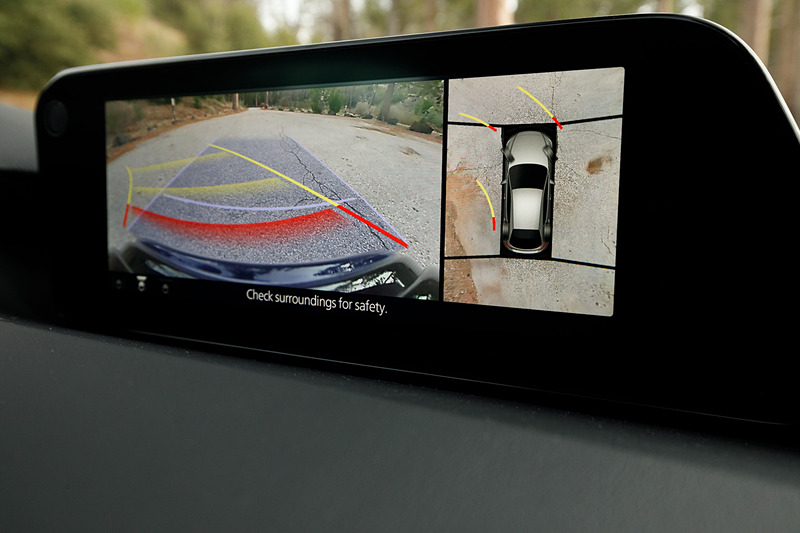 5ドアハッチバックのインテリア。新型Mazda3のコクピットはすべてをドライバーを中心に左右対称にレイアウト。ステアリングスポークやセンターディスプレイなど、パーツ単位で「バニシングポイント」（遠近法で言う収束点）に基づいてデザイン。また、本革にはマツダ独自のシボを採用したほか、シフトパネルにはレーザー加工で柄を刻み込んだ黒のメタリック層と、まっすぐ光を透過・減衰させるカラークリア層からなる2層成形と呼ばれる技術を採用