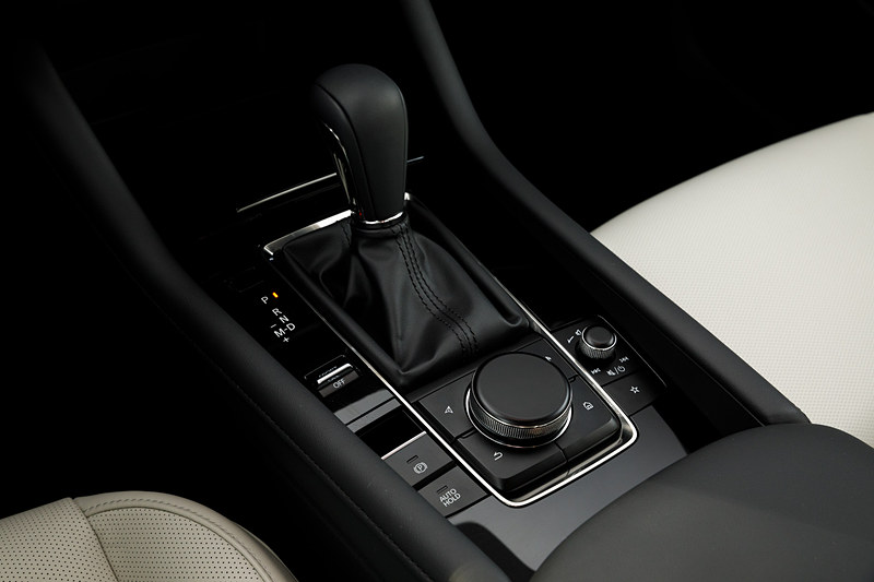 4ドアセダンのインテリア。5ドアハッチバックともどもマツダらしくドライビングポジションにもこだわり、ステアリングのテレスコピック量を前後10mmずつ拡大し、合計で70mmの調整幅を持たせることで体格に応じたドライビングポジション調整の精度を高めた。シフト位置は現行モデルに対してAT/MTともに前方・上方に移動させ、ステアリングからの持ち替えのしやすさとシフト操作のしやすさを向上させたという