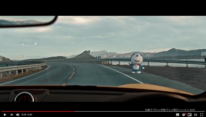 イエローのオープンカーでドライブする福山雅治さんが道路脇で手を上げる「ドラえもん」を発見。福山さんがドラえもんに「未来のタイヤ」について質問するCM内容となっている