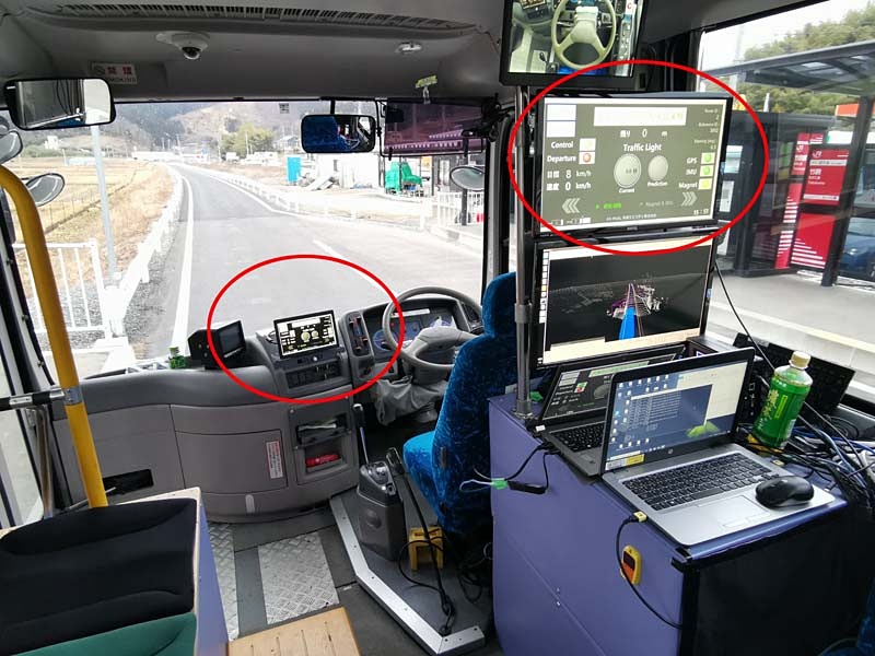 日本信号が設置した信号制御装置（左）。報道関係者用に設置された信号情報を可視化するための信号機（中央）。実際には無線で車両に信号が届くのでこのような信号機の設置は無用である。車内運転席横と運転席背面モニタに信号が点灯する（右）