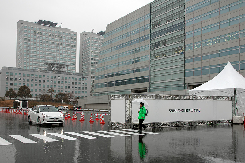 クルマと歩行者の両方に自らの位置を発信する装置を付けて、お互いが通信しあうことで、物陰でも接近が感知できるシステムのデモ。歩行者として体験できる