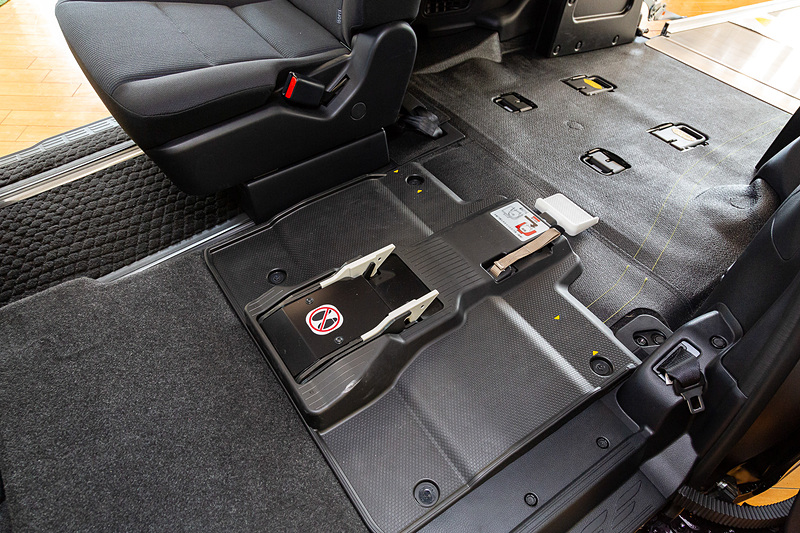 固定方法は白いラッチの部分まで車いすを推し進め、下面のバーを押し当てるだけ。あとはクルマが動く振動でラッチがバーを噛み、車いすがガッチリと固定される仕組み