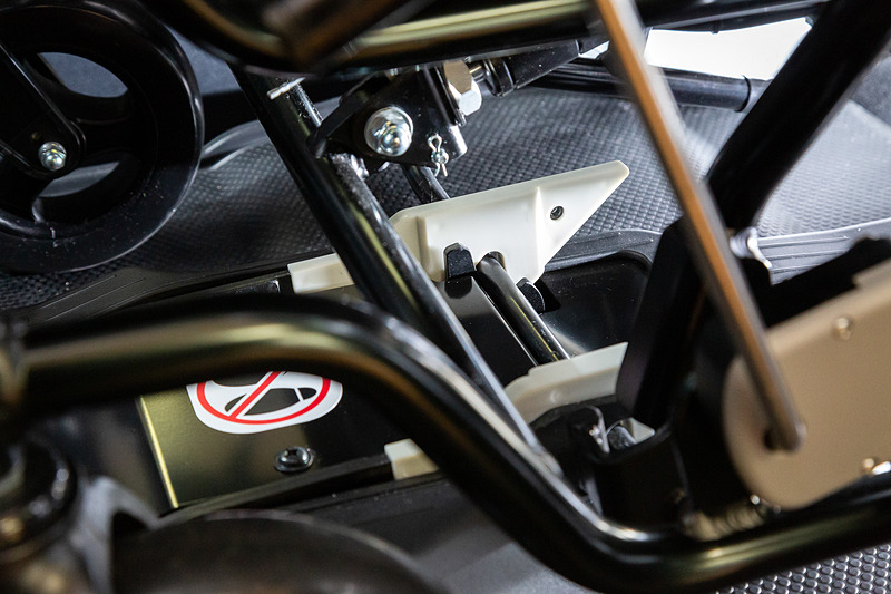 固定方法は白いラッチの部分まで車いすを推し進め、下面のバーを押し当てるだけ。あとはクルマが動く振動でラッチがバーを噛み、車いすがガッチリと固定される仕組み