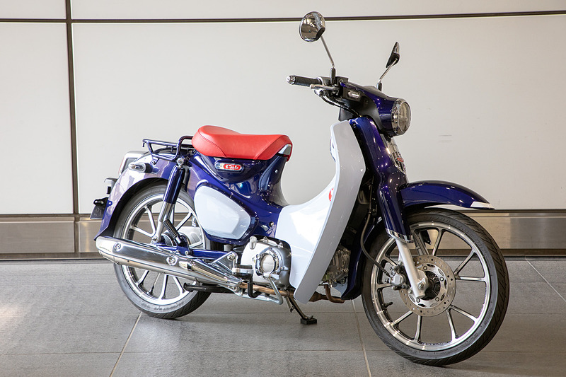 クロスカブ50はレグシールドがないので積むのが楽。車体を右寄りにできるからハンドルが真っすぐで固定できる。クロスカブ110も同様だろう。スーパーカブC125（写真右）は小振りなレグシールドがあるので、積載イメージはCB125Rと同じ感じだと思われる