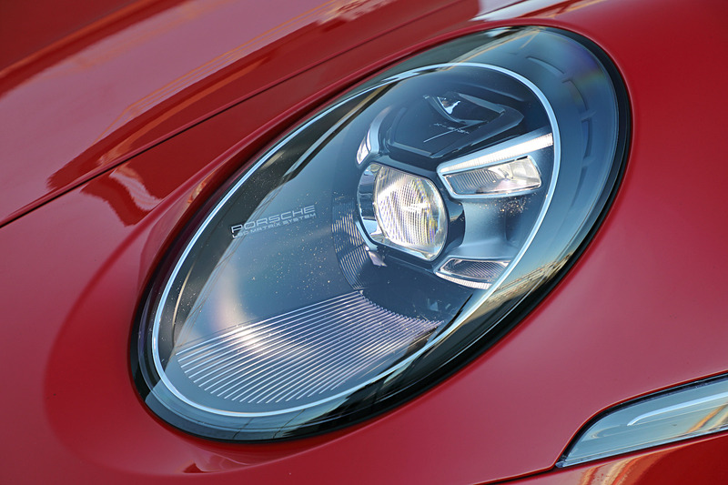 新型911のフロントボディは従来から45mmワイド化されるとともに、ドアと面一の電動ポップアウトハンドルの採用によってテーパーの付いた滑らかなサイドラインを際立たせるデザインに仕上げた。また、初代911を彷彿とさせる新しいLEDヘッドライトを採用したほか、リアまわりではワイドな可変式リアスポイラーとエレガントなシームレスのライトバーを備えるのが特徴