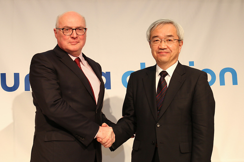 記者会見の最後に握手するフォルシア CEO パトリック・コラー氏（左）とフォルシア クラリオン エレクトロニクス EVP 川端敦氏（右）