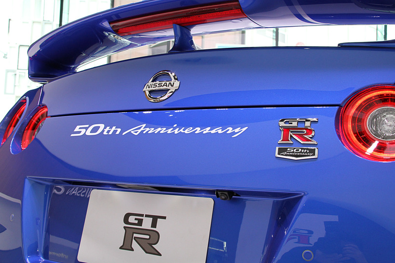 リアまわりに「GT-R 50th Anniversary」の文字をあしらったバッヂとステッカーを装着。ワンガンブルーのモデルでは、ボディカラーとコーディネートして設定した50周年記念ロゴ入りのブルースポークホイールを標準装備。タイヤはダンロップ「SP SPORT MAXX GT600 DSST CTT」（フロント：255/40ZRF20、リア：285/35ZRF20）