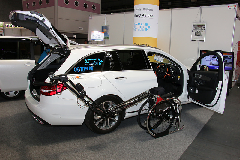 車いす収納ロボットアーム「TMN R11」を装着した「Cクラス ステーションワゴン」を展示。4.7m以上の全長を持つこのモデルの運転席横からラゲッジスペースに車いすを収納する長いアームを、ボディとのクリアランスを一定に保ちつつ、大きく横側に張り出さず動かせることがポイントとなっている