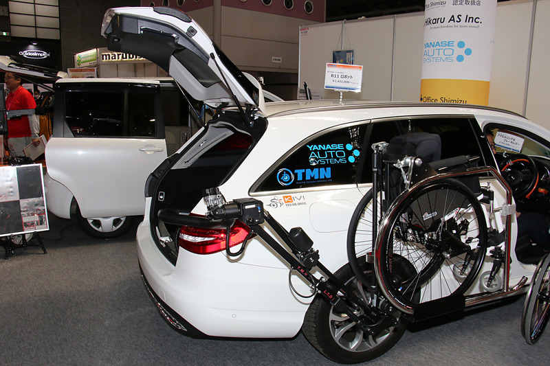 車いす収納ロボットアーム「TMN R11」を装着した「Cクラス ステーションワゴン」を展示。4.7m以上の全長を持つこのモデルの運転席横からラゲッジスペースに車いすを収納する長いアームを、ボディとのクリアランスを一定に保ちつつ、大きく横側に張り出さず動かせることがポイントとなっている