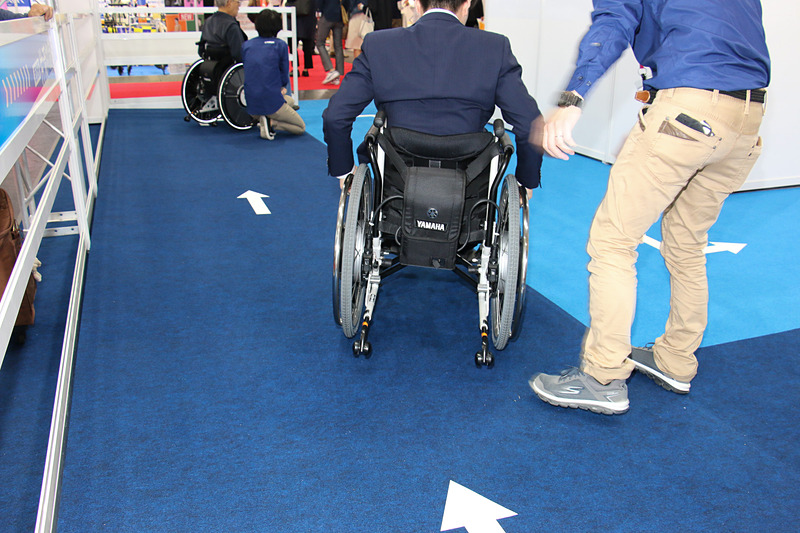 右肩下がりに設定された特設スペースでJWスウィングの体感試乗を実施。「片流れ制御」をOFFにした状態では、とくに若い男性などが乗っているとアシストが働きすぎてしまい、怖いぐらいの勢いで車いすが右旋回していく。これをモーターアシストの補正で直進させるのが片流れ制御となる