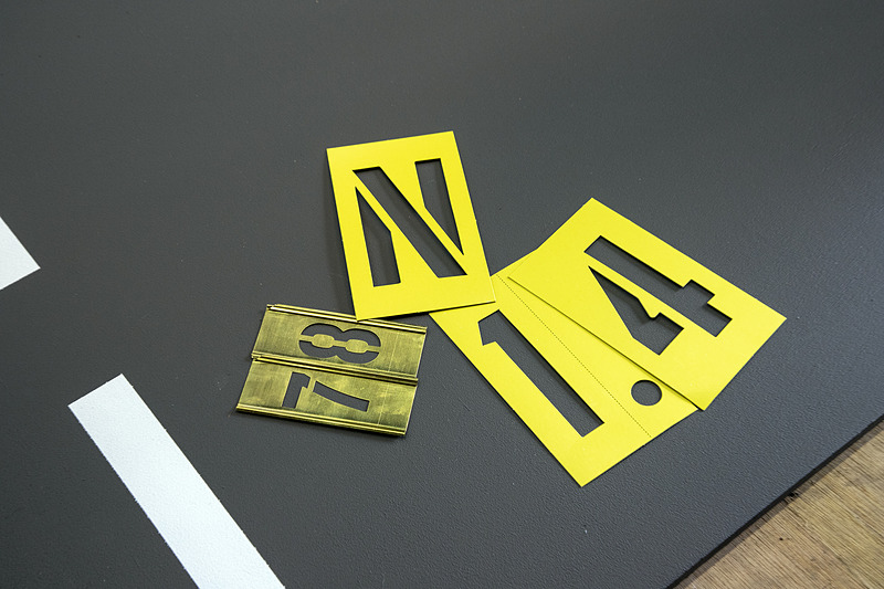 数字や文字は「ステンシル」という塗装用の抜き文字板を使用。紙製、金属製、樹脂製がある。安価なのは紙製だが数回使うとだめになる感覚。また、反りもあるので文字がキレイに出ないこともある