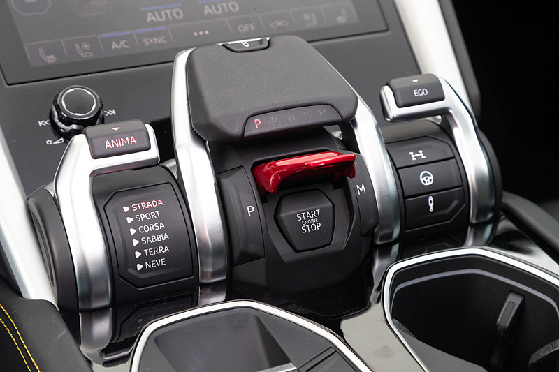 レザー、アルカンターラ、アルミニウム、カーボンファイバー、ウッドなどの高品質素材を用いたインテリア。ウルスの走行モードはオンロード向けの「STRADA」「SPORT」「CORSA」が基本で、撮影車はオプション設定の「SABBIA（砂漠）」「TERRA（オフロード）」「NEVE（雪上）」も付いていた